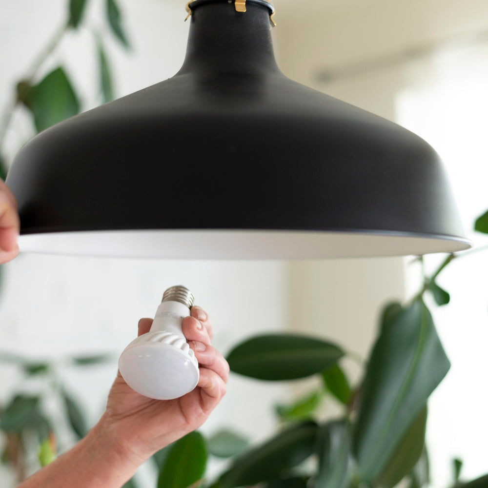 close up of hands changing led light bulb