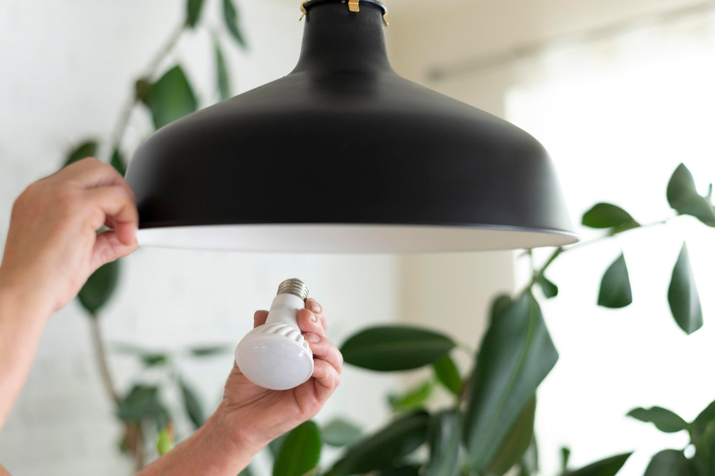 close up of hands changing led light bulb